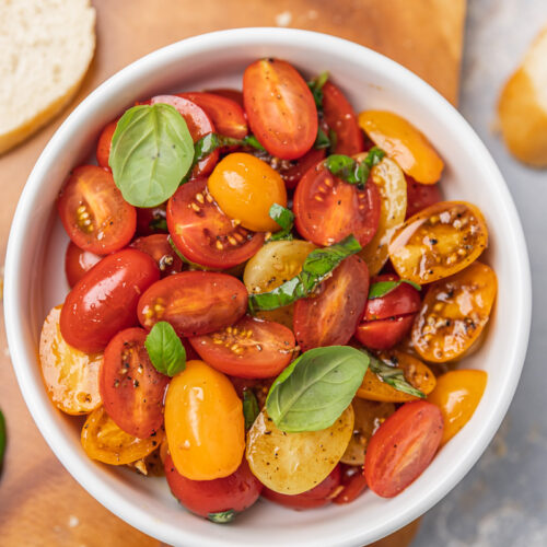 a bowl of marinated tomatoes on serving board.