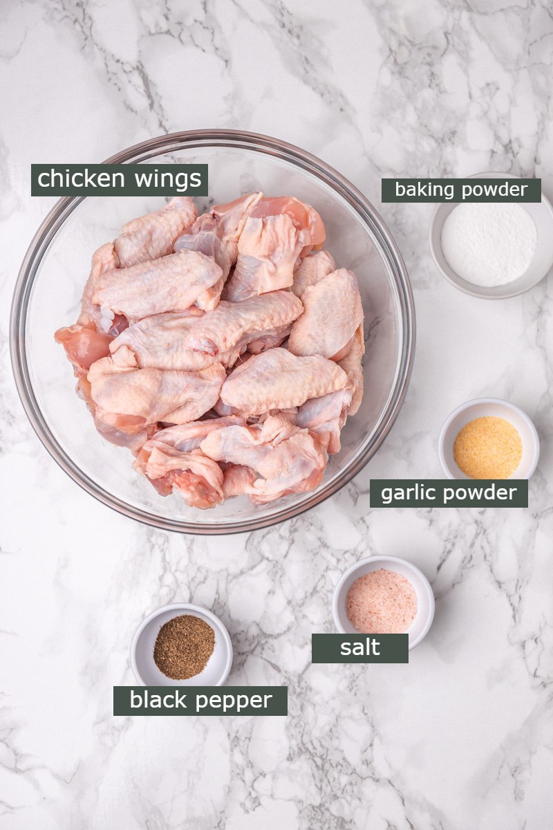 ingredient laid out on a worktop, chicken wings, salt, pepper, garlic powder and baking powder.