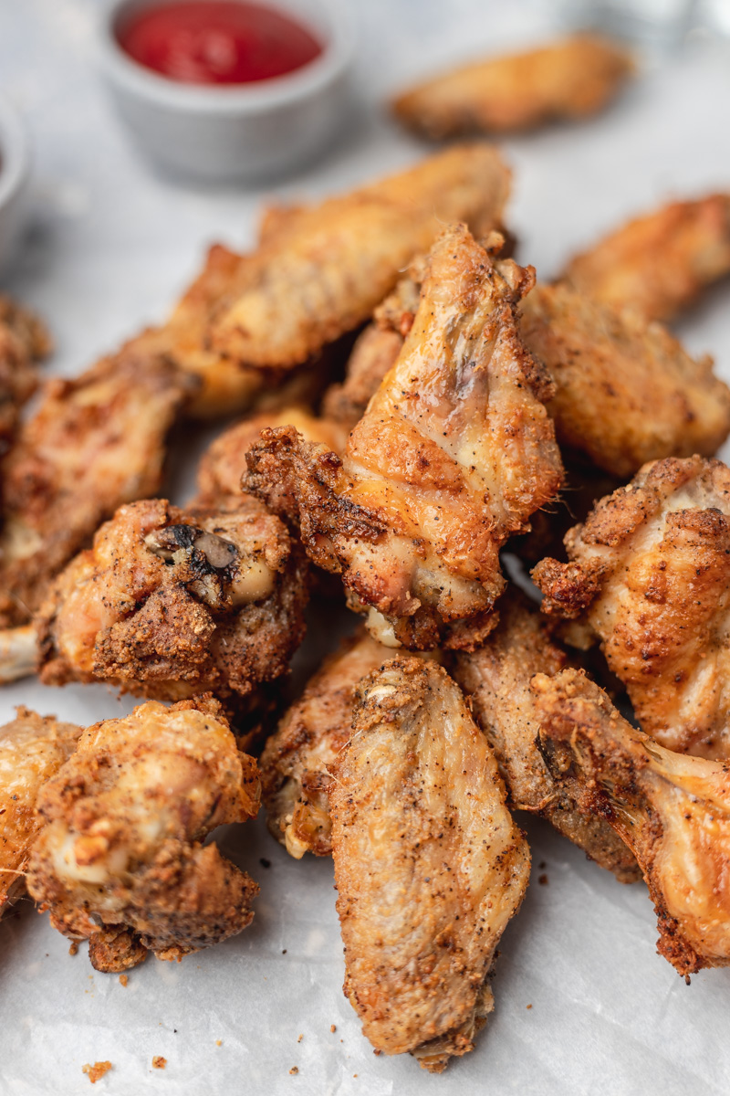 a close shot of crispy and golden brown wings oiled on a parchment paper.