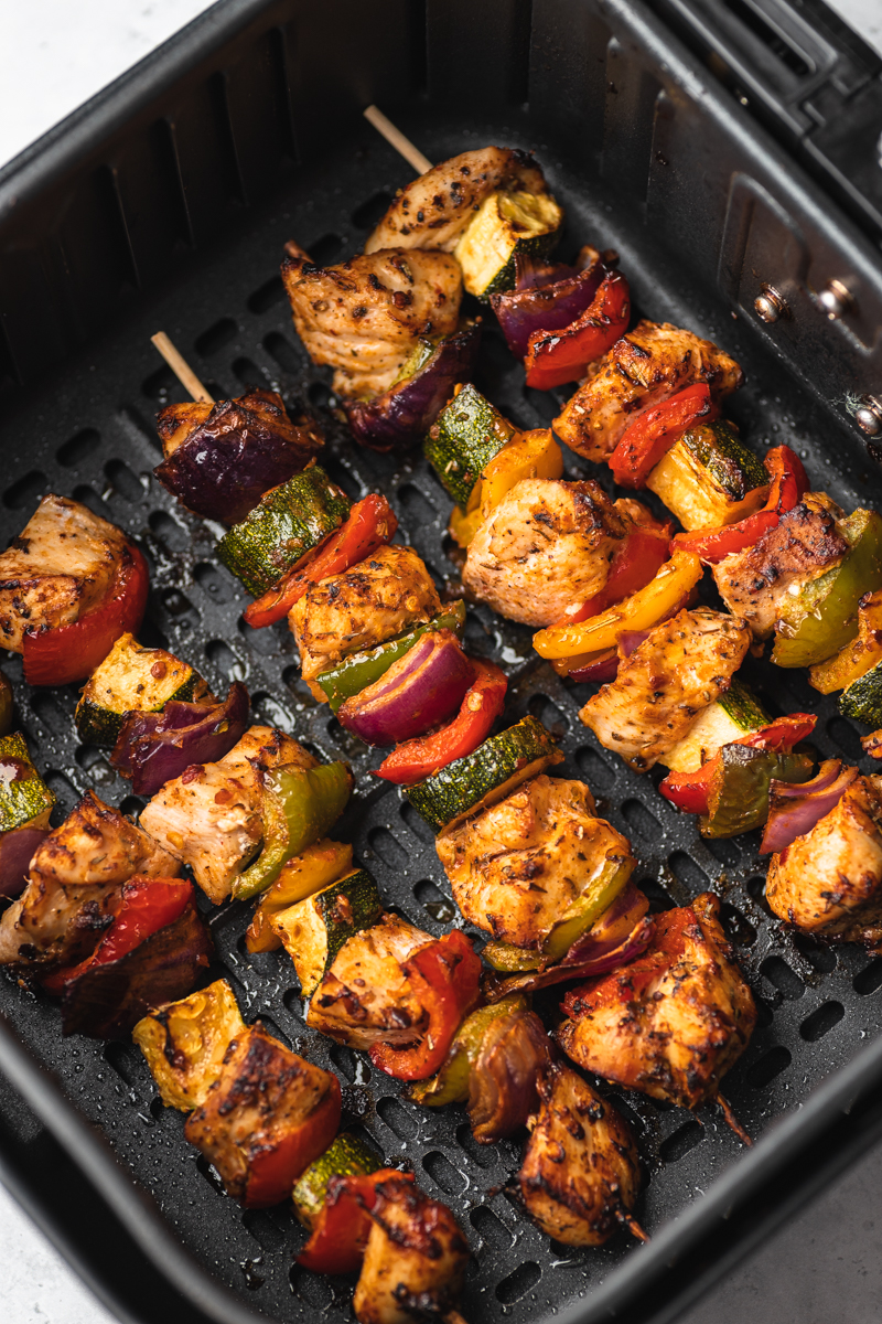 cooked five chicken skewers in an air fryer basket.