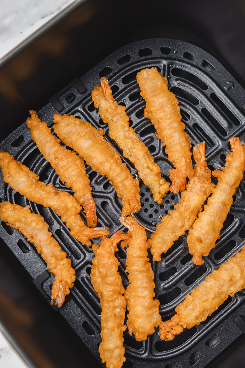 cooked tempura shrimp in the air fryer basket.