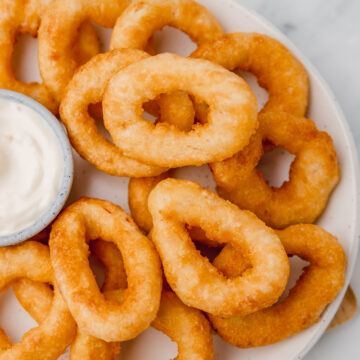 onion rings and a small pot of dip on a plate.