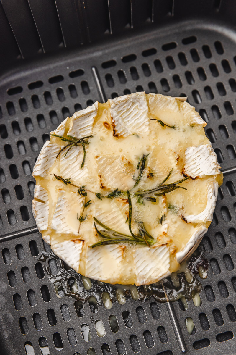 cooked camembert cheese in an air fryer basket.