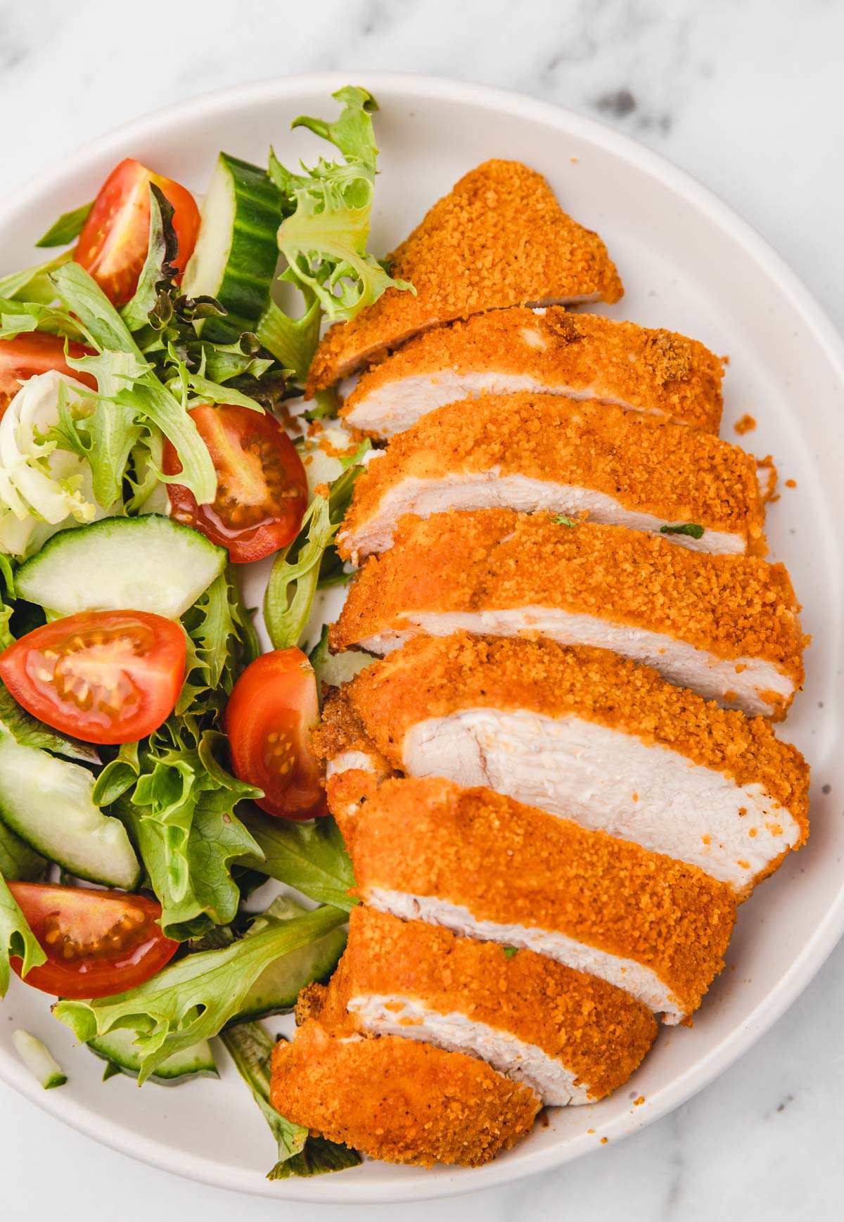 a plate of sliced breaded chicken breast and salad.