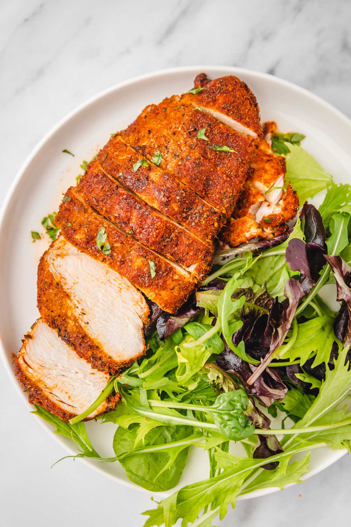 sliced chicken breast and salad on a white plate.