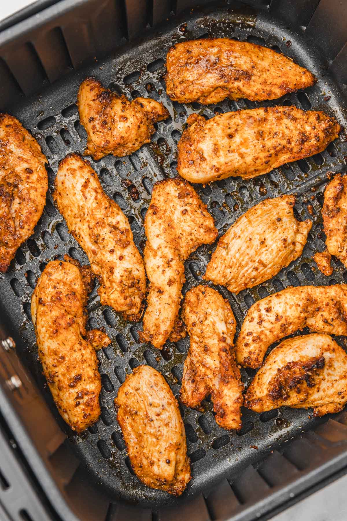 cooked chicken fingers in air fryer basket.