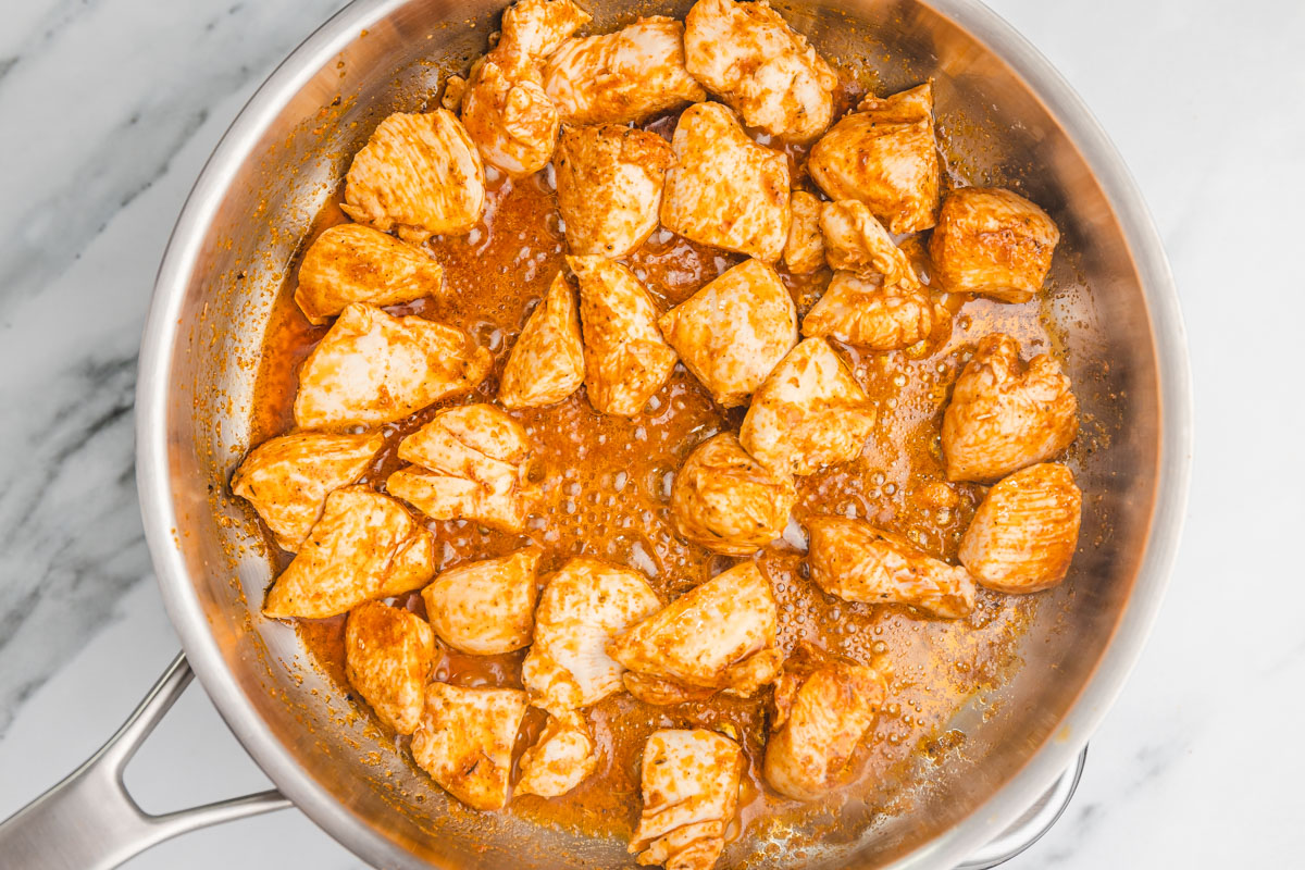 cubed chicken breast cooking in a skillet.