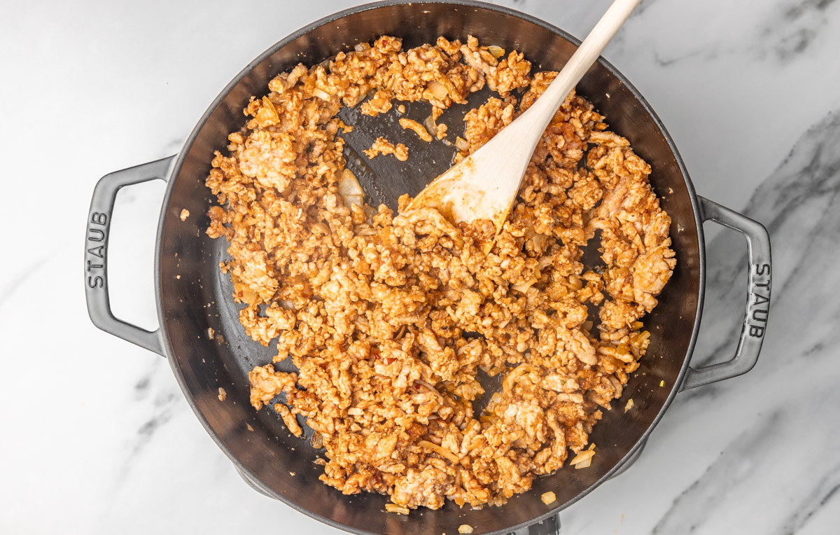 cooked ground chicken in a skillet with a wooden ladle