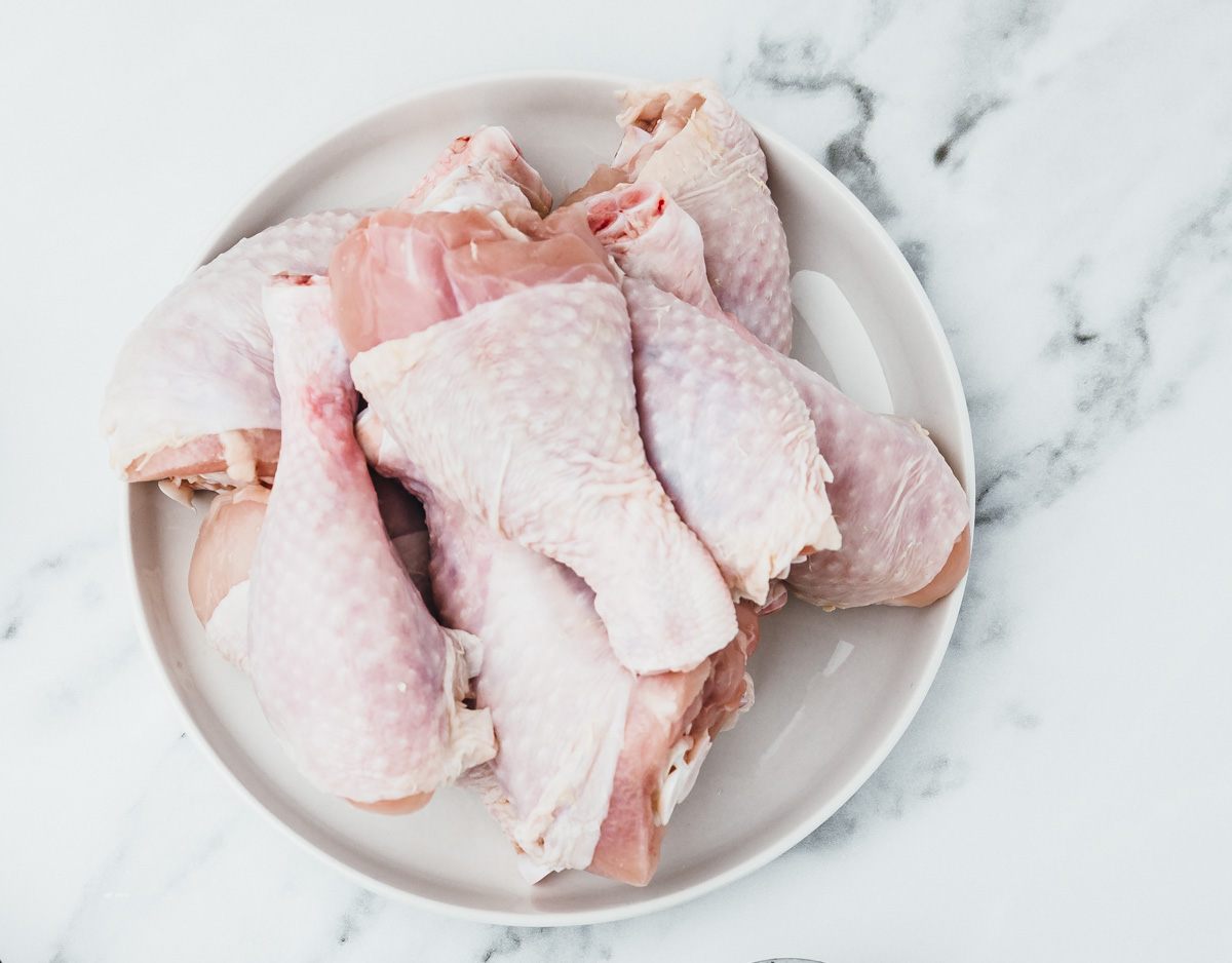 raw chicken drumsticks on a plate