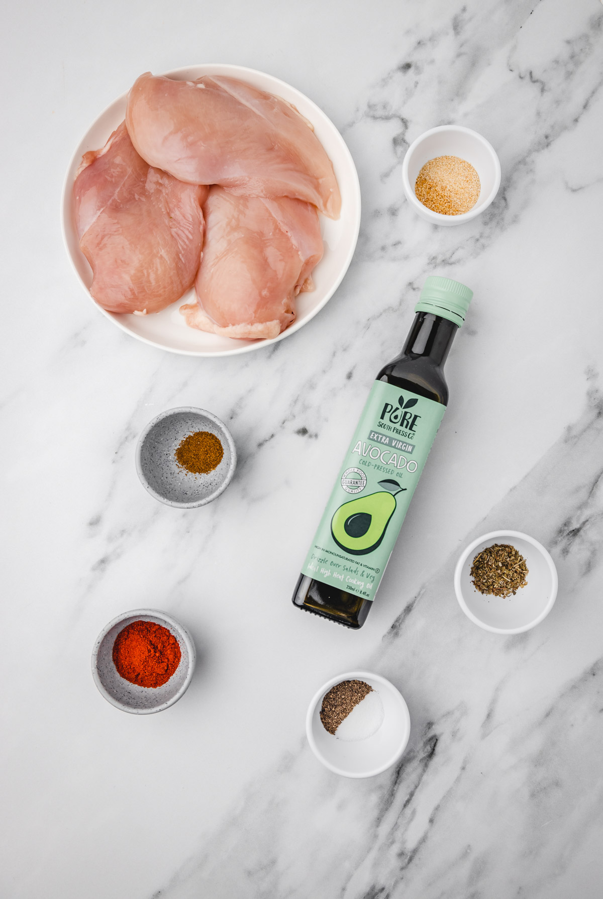 ingredients needed to make juicy chicken breast on a marble surface.