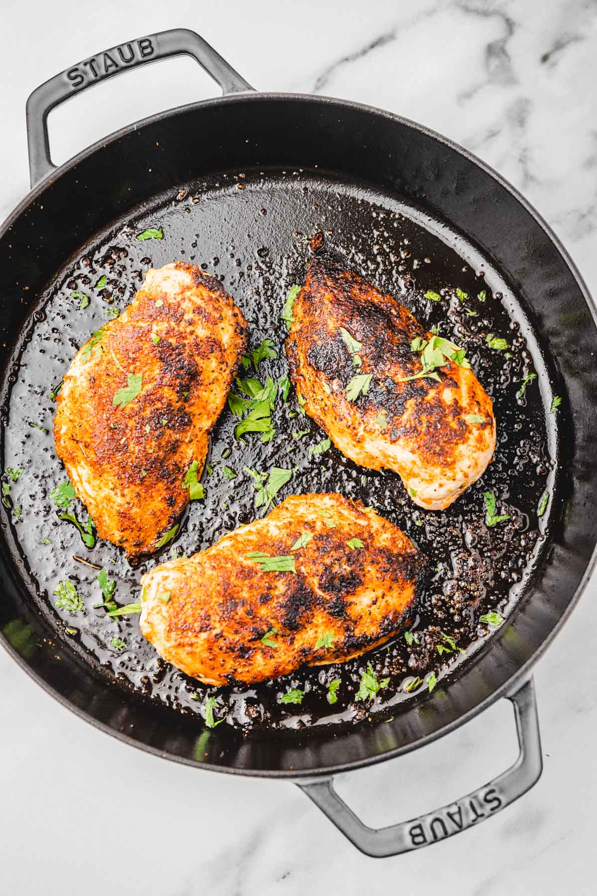 cooked juicy three chicken breasts in a cast iron skillet.