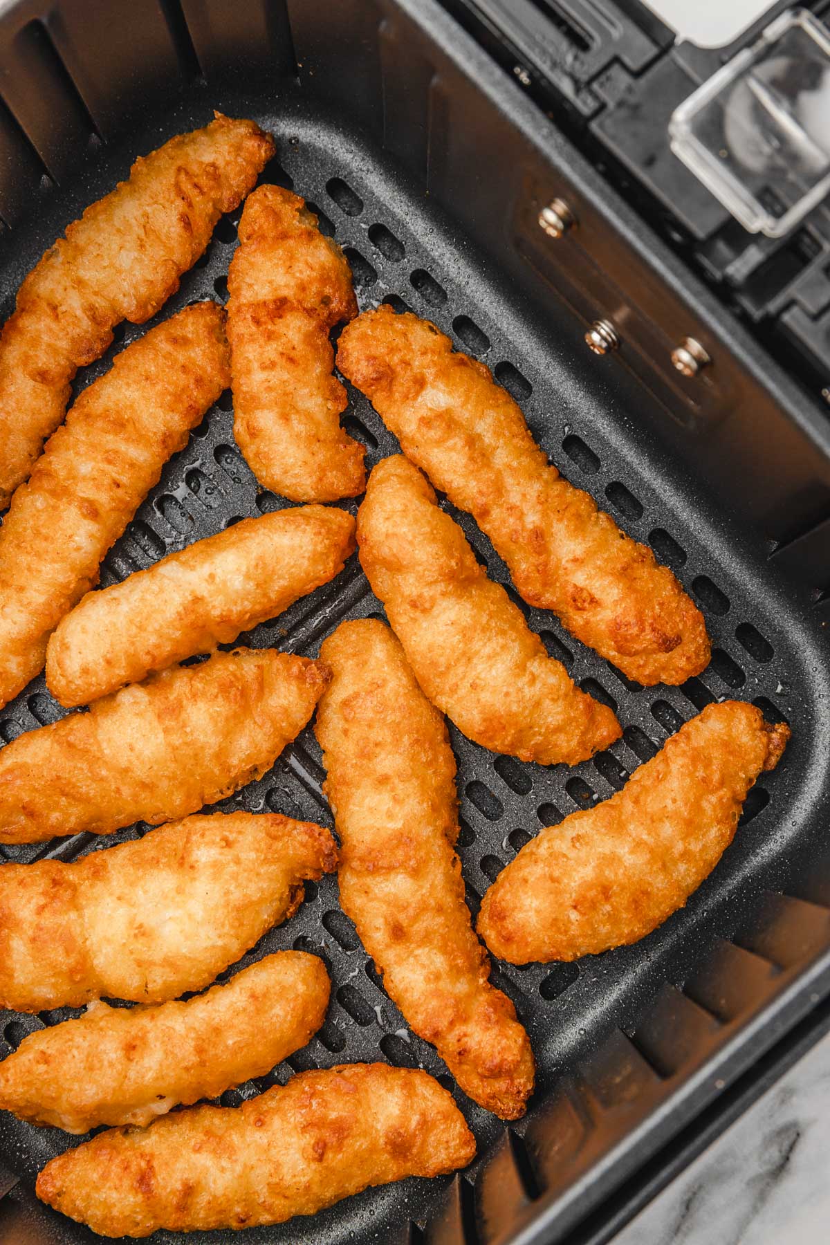 chicken strips in an air fryer basket.
