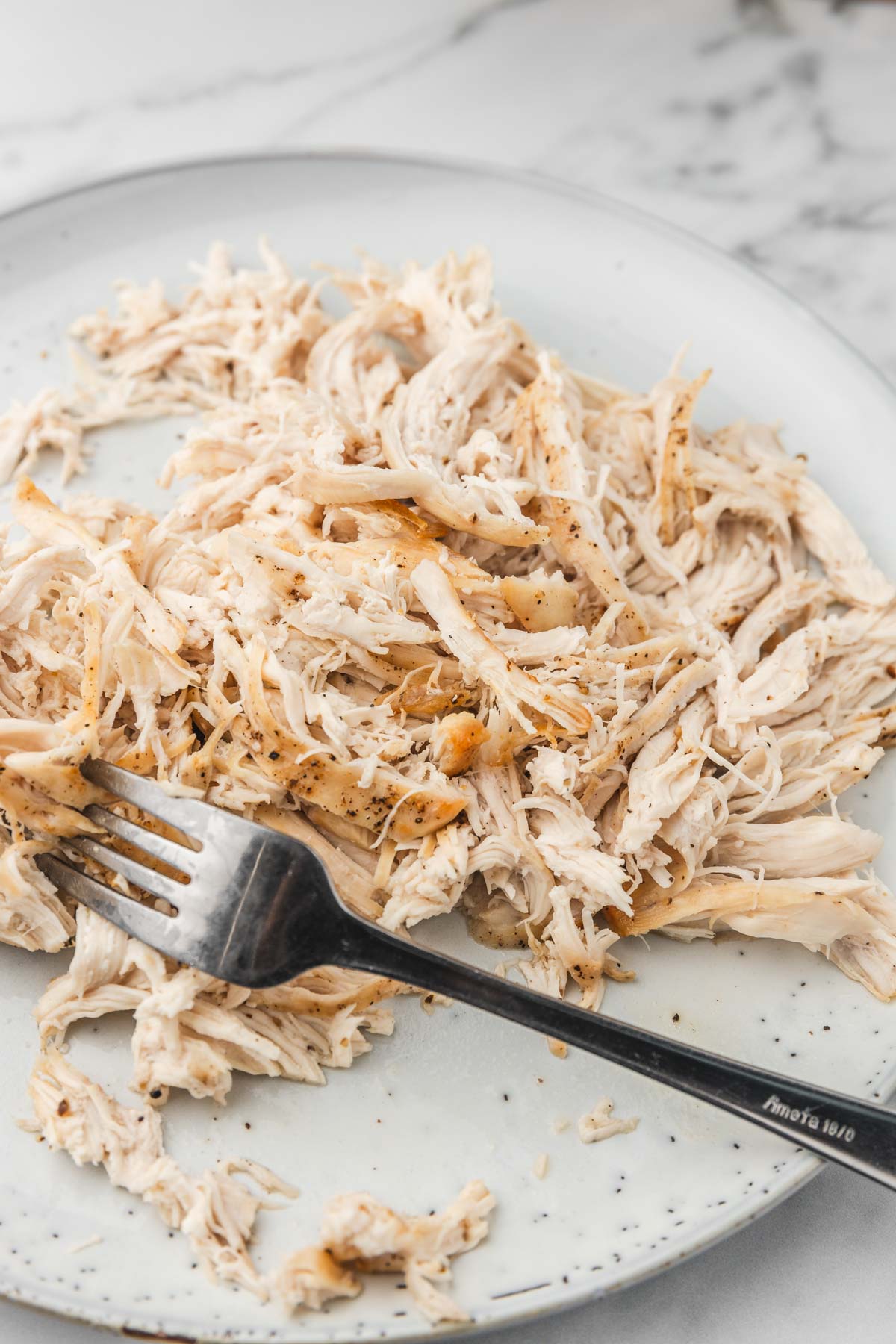 shredded chicken breast with a fork on a plate.