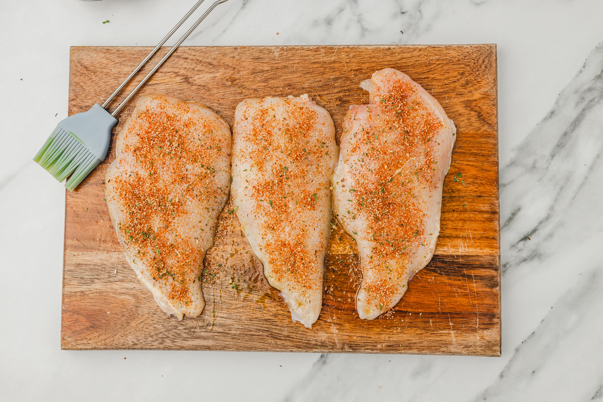 seasoned raw chicken on a chopping board.