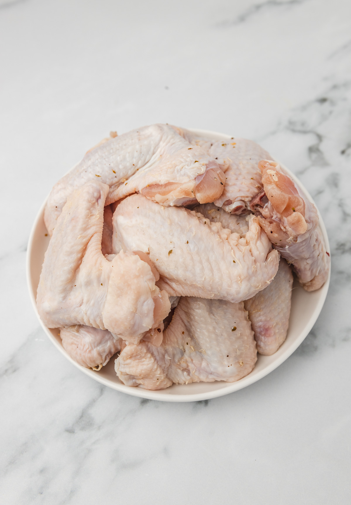 uncooked chicken wings in a plate.