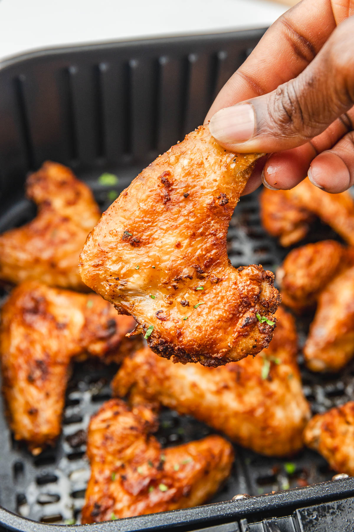 a hand holding cooked brined chicken wings.